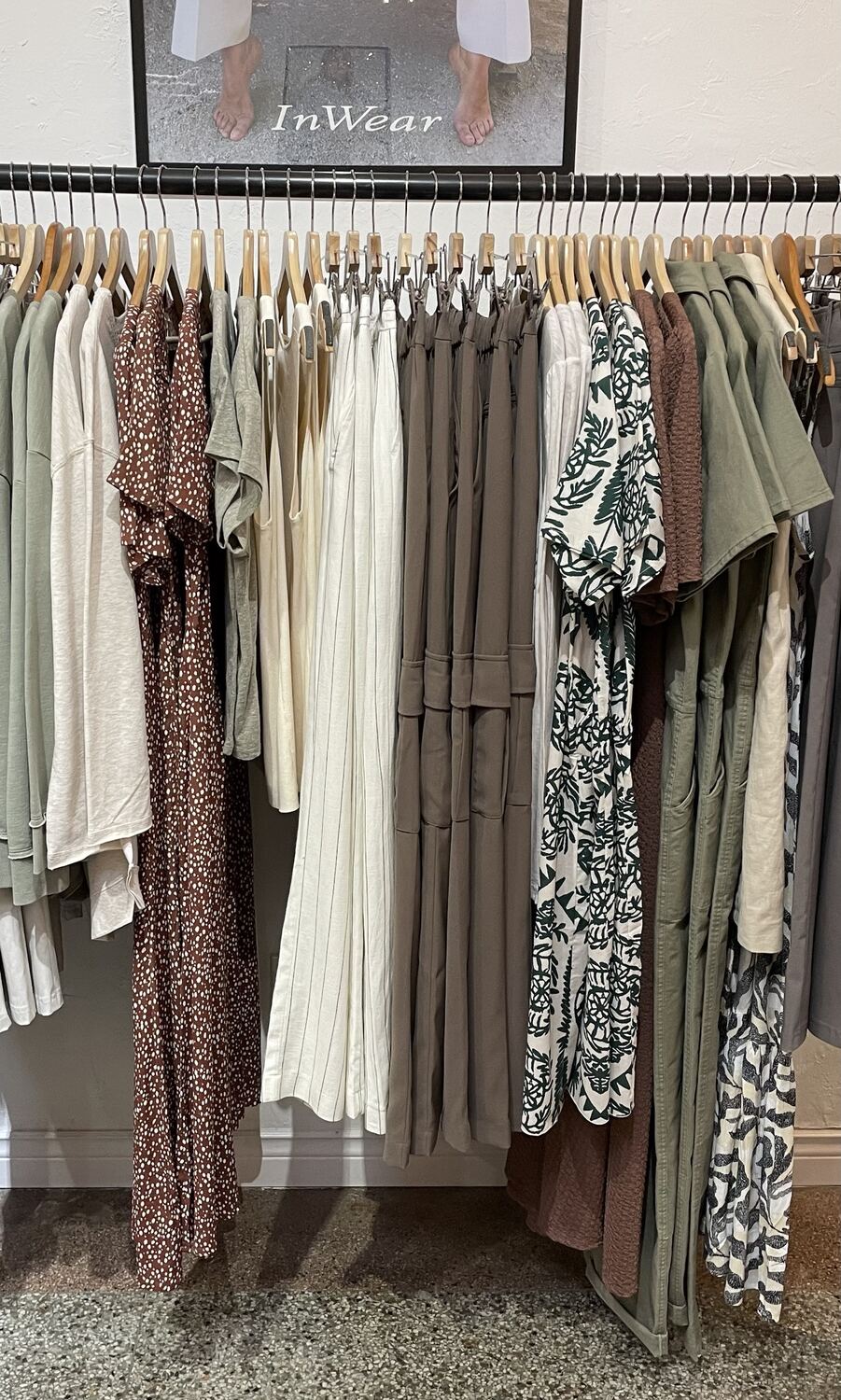 A rail of sage green, cream and chocolate brown pieces with dotted and leaf-print dresses