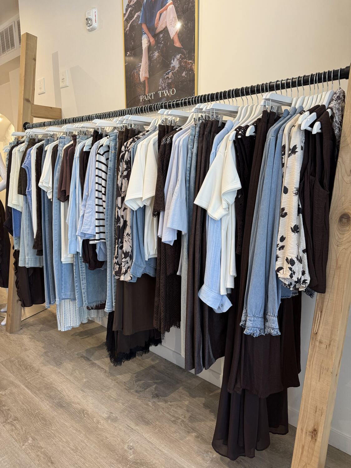 A long rail of light denim, espresso brown and ivory pieces under a framed poster